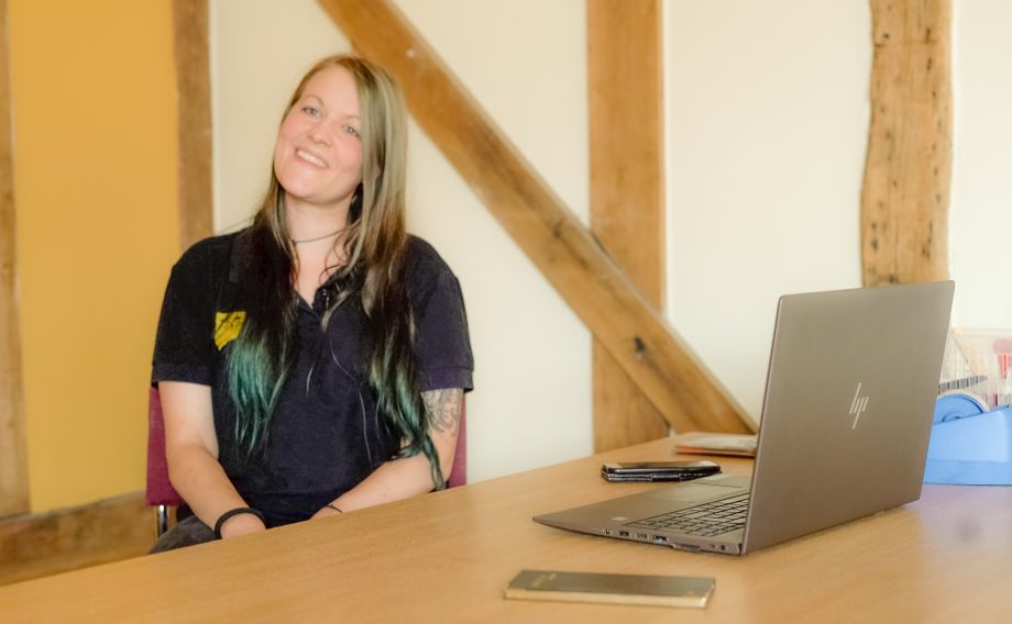 A Freedom Project team member sitting by their laptop smiling at the camera.